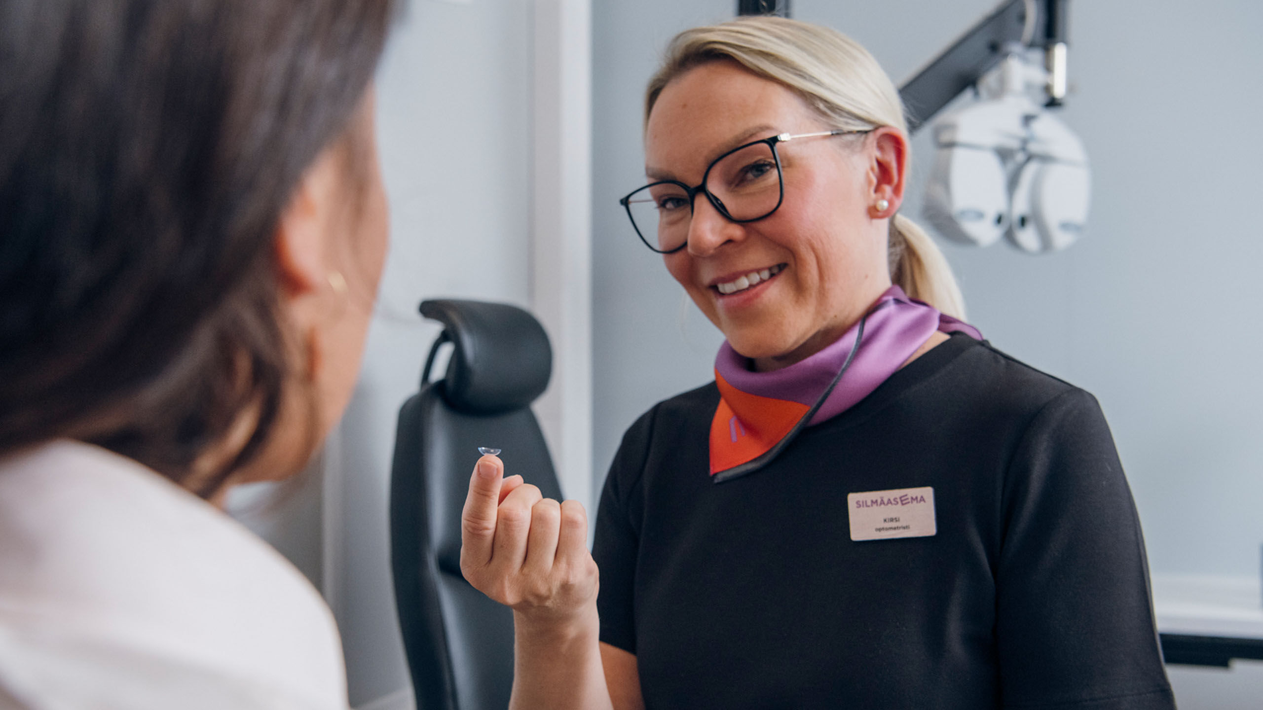 Optikko keskustelee asiakkaan kanssa piilolinsseist&auml;.